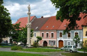 Statue auf einer Säule vor bunten Häusern in Drosendorf.